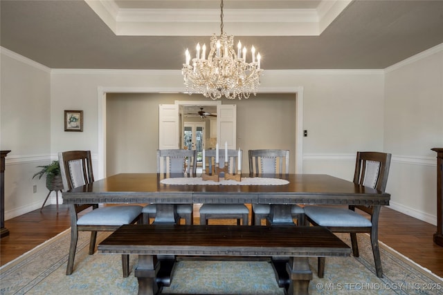 dining room with hardwood / wood-style floors, ornamental molding, and a raised ceiling