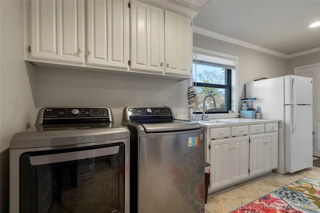 washroom with sink, washing machine and clothes dryer, crown molding, and light tile patterned floors