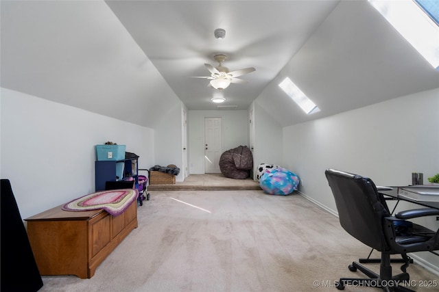 carpeted office space with vaulted ceiling with skylight and ceiling fan