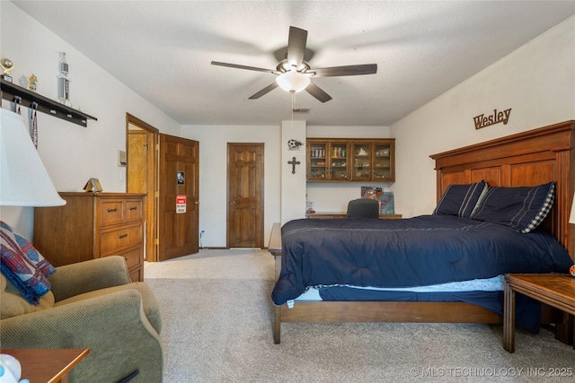 carpeted bedroom with ceiling fan and a textured ceiling