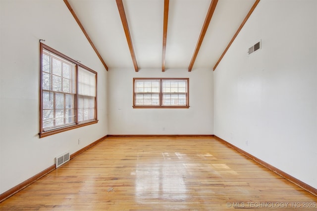 spare room featuring light hardwood / wood-style floors and lofted ceiling with beams