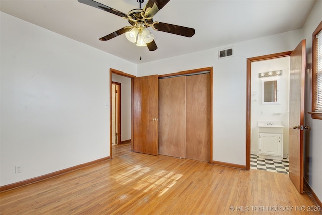 unfurnished bedroom with light hardwood / wood-style floors, a closet, ensuite bath, and ceiling fan