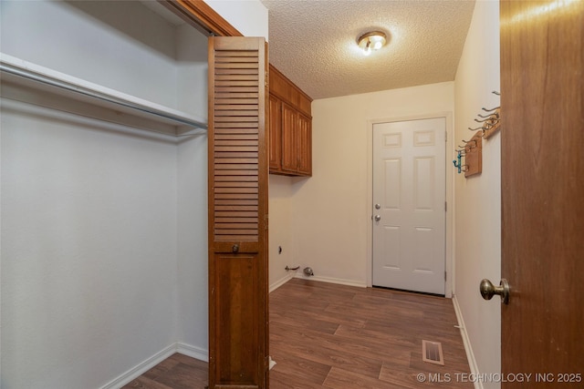 laundry area featuring a textured ceiling, dark hardwood / wood-style floors, and cabinets