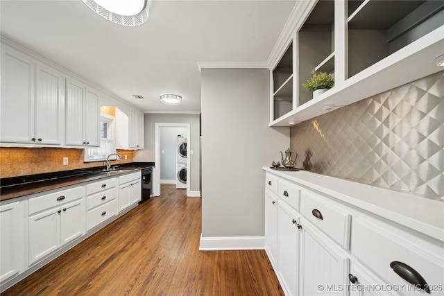 kitchen featuring dishwasher, backsplash, dark wood-type flooring, white cabinetry, and stacked washer and clothes dryer