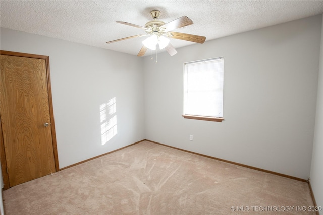 spare room featuring ceiling fan, a textured ceiling, and carpet