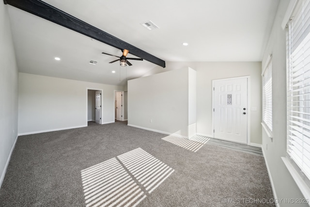 entryway featuring dark colored carpet, a healthy amount of sunlight, and vaulted ceiling with beams