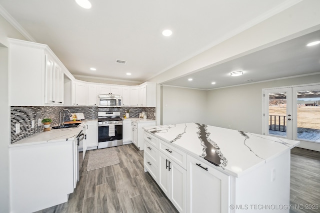 kitchen featuring french doors, crown molding, stainless steel appliances, light stone countertops, and white cabinets