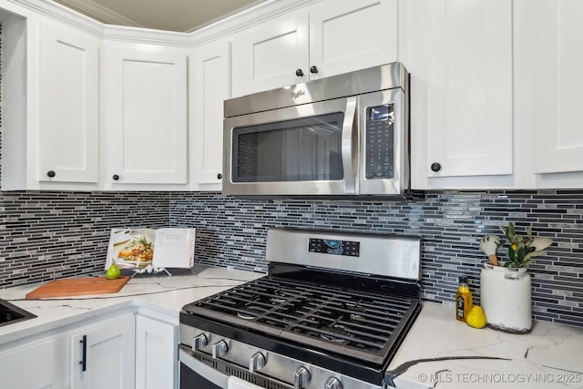 kitchen featuring light stone counters, stainless steel appliances, and white cabinets