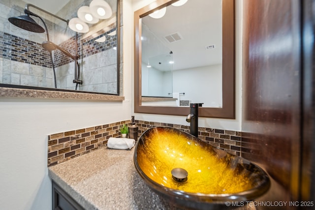 interior space featuring a tile shower, vanity, and backsplash