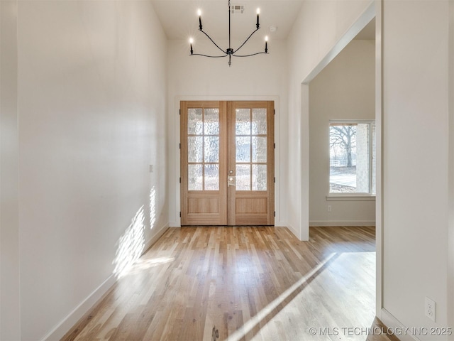 entryway with visible vents, baseboards, french doors, light wood-style floors, and a notable chandelier