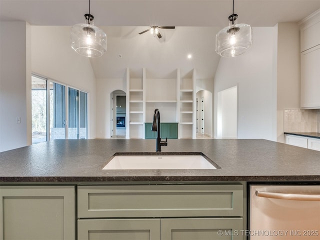 kitchen featuring dark countertops, a sink, arched walkways, hanging light fixtures, and stainless steel dishwasher