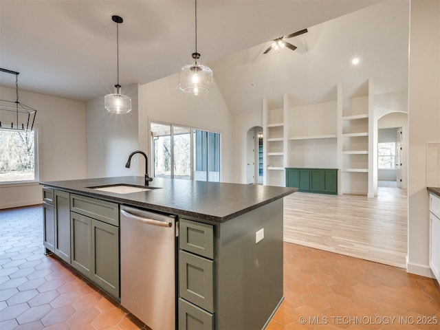 kitchen featuring arched walkways, stainless steel dishwasher, dark countertops, and a sink