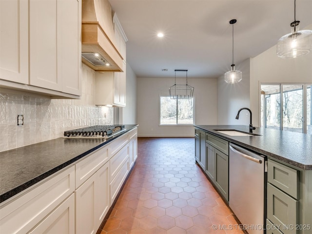 kitchen featuring pendant lighting, custom range hood, a sink, appliances with stainless steel finishes, and decorative backsplash