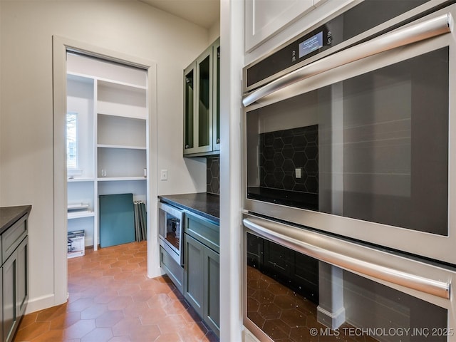 kitchen featuring dark countertops, decorative backsplash, stainless steel appliances, and light tile patterned flooring