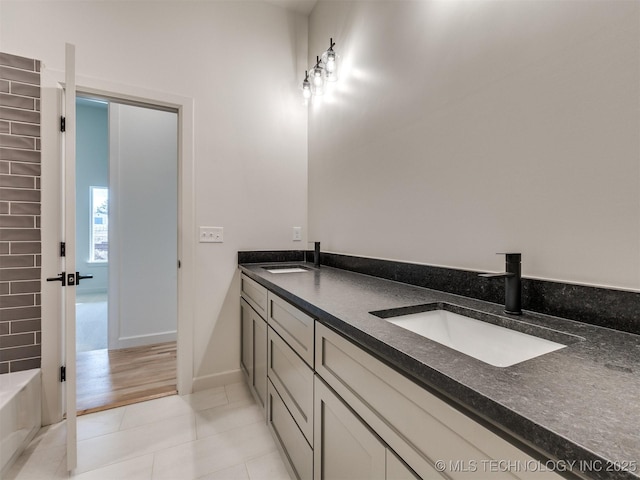 full bath with tile patterned floors, double vanity, baseboards, and a sink