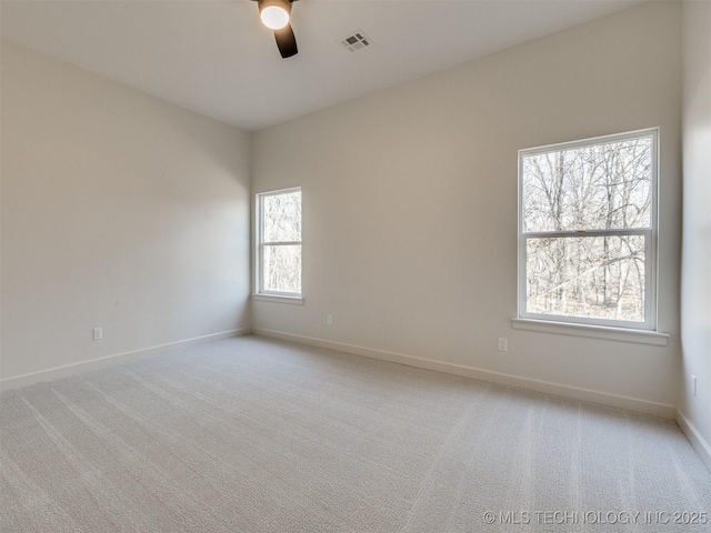 empty room with visible vents, light colored carpet, a ceiling fan, and baseboards