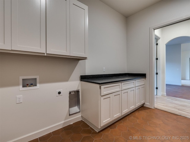 washroom with baseboards, washer hookup, arched walkways, cabinet space, and hookup for an electric dryer