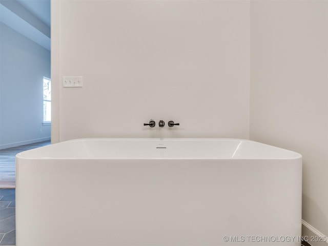 full bath featuring baseboards and a freestanding bath