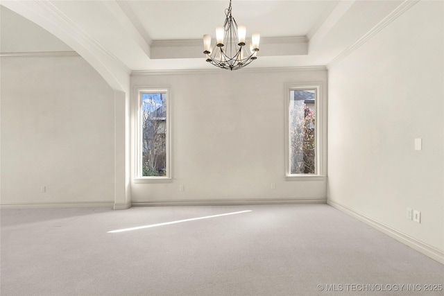 carpeted empty room with a notable chandelier and a raised ceiling