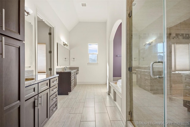 bathroom featuring a shower with shower door, lofted ceiling, and vanity