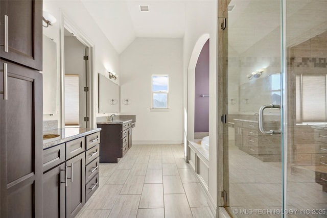 bathroom featuring a sink, a stall shower, two vanities, visible vents, and lofted ceiling