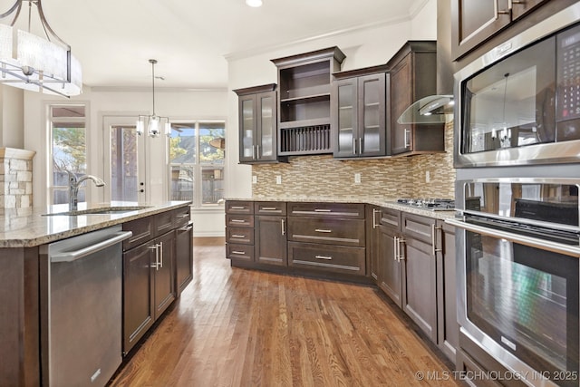 kitchen with an inviting chandelier, a sink, stainless steel appliances, decorative backsplash, and dark brown cabinets