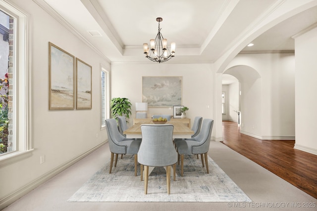 dining area featuring a healthy amount of sunlight, arched walkways, an inviting chandelier, and crown molding