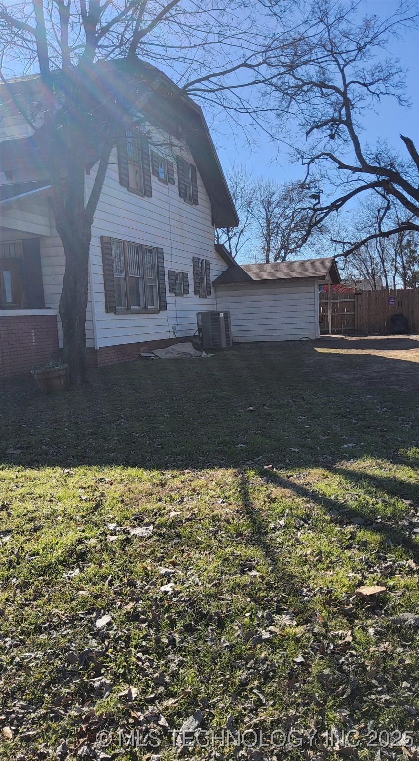 view of side of property with cooling unit and a yard