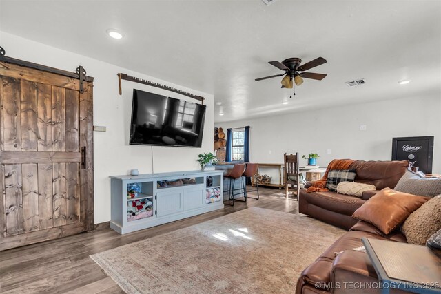 living room featuring hardwood / wood-style flooring, a barn door, and ceiling fan