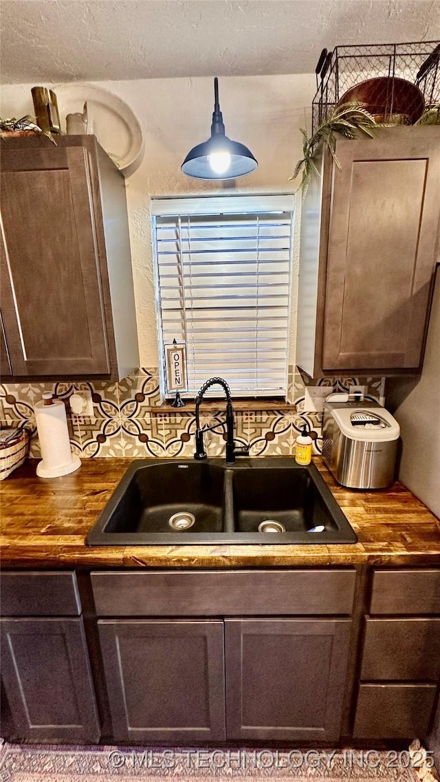 kitchen featuring dark brown cabinetry, butcher block counters, sink, and decorative backsplash