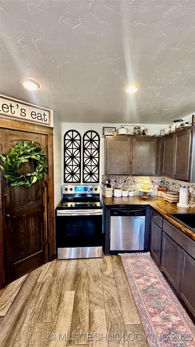 kitchen with appliances with stainless steel finishes, sink, dark brown cabinets, and backsplash