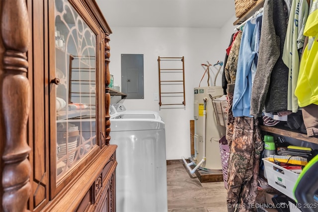 clothes washing area featuring washing machine and dryer, electric water heater, electric panel, and light hardwood / wood-style flooring