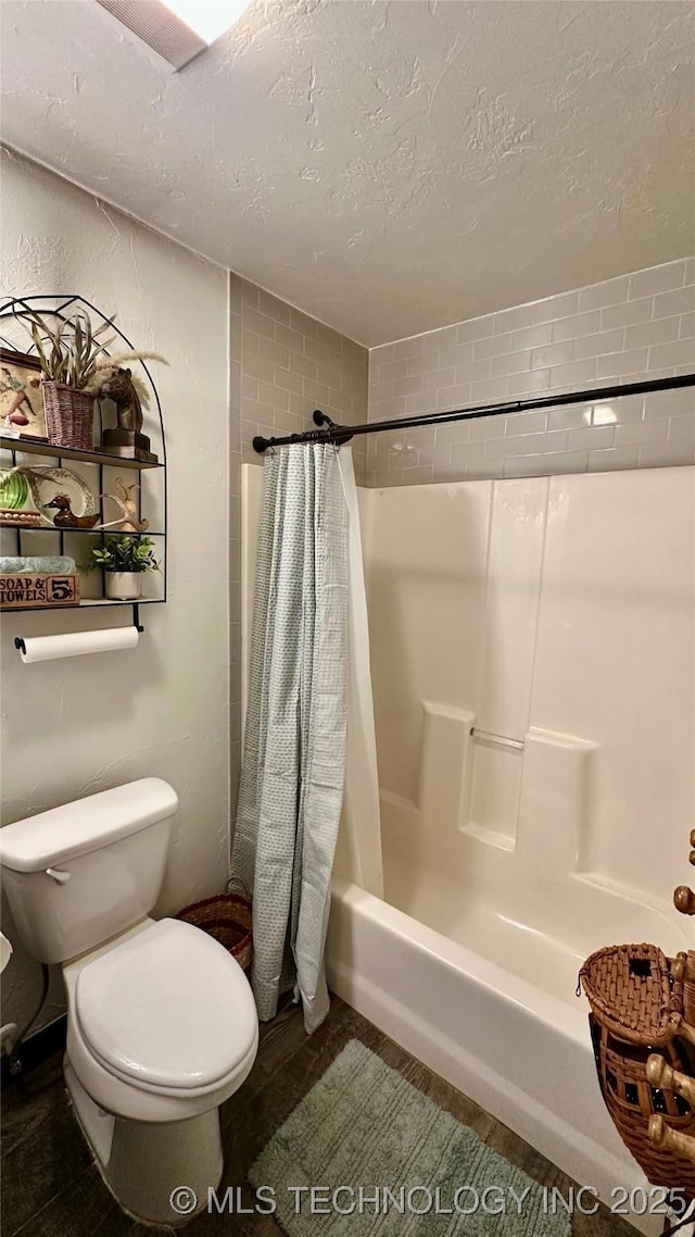 bathroom with shower / bath combination with curtain, toilet, and a textured ceiling