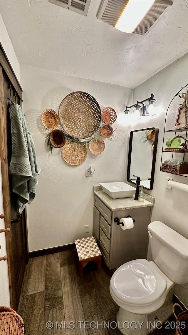 bathroom with hardwood / wood-style flooring, a skylight, vanity, and toilet