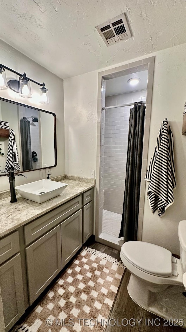 bathroom with hardwood / wood-style floors, vanity, toilet, a textured ceiling, and a shower with curtain