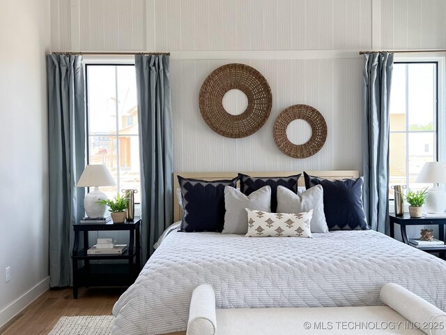 bedroom featuring multiple windows, baseboards, and wood finished floors