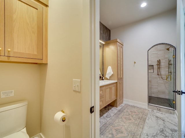 bathroom featuring vanity, a shower with shower door, and toilet