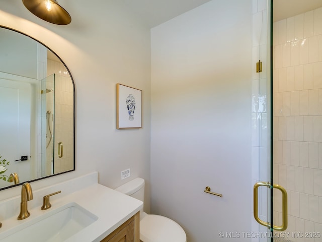 bathroom featuring vanity, an enclosed shower, and toilet