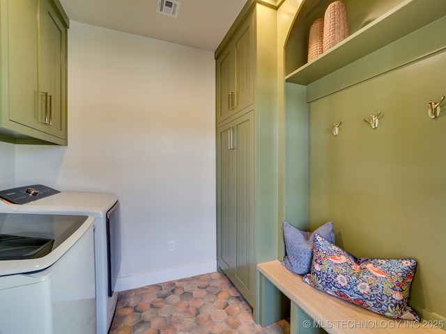 clothes washing area with cabinets, washer and dryer, and light tile patterned floors