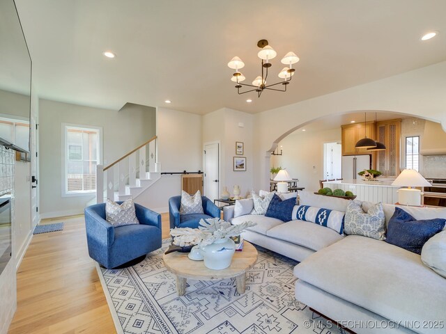 living room with light wood-type flooring, a notable chandelier, and plenty of natural light