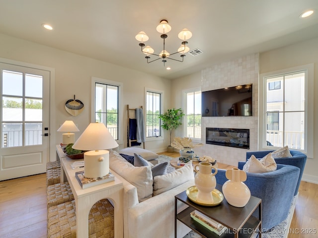 living room with a fireplace, recessed lighting, visible vents, light wood-style flooring, and a chandelier