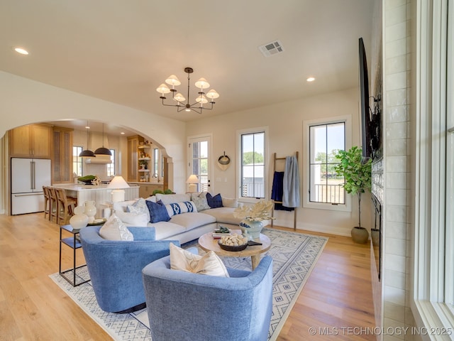 living room featuring a notable chandelier, a wealth of natural light, and light wood-type flooring