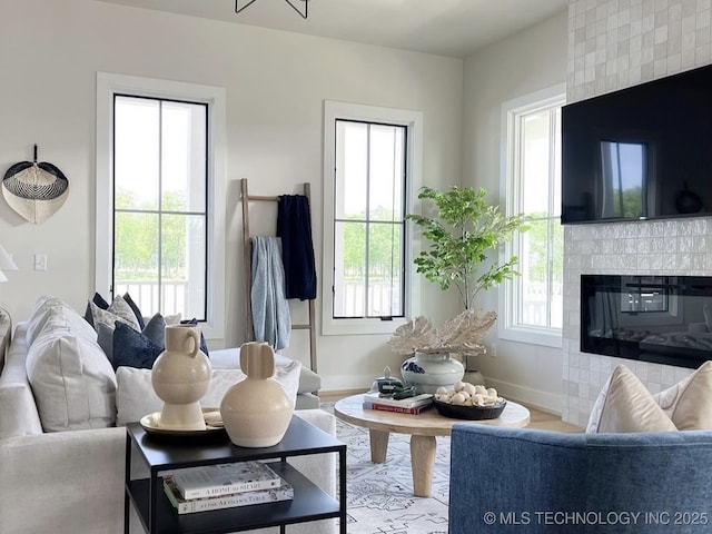 living room with a tiled fireplace, light hardwood / wood-style flooring, and a wealth of natural light