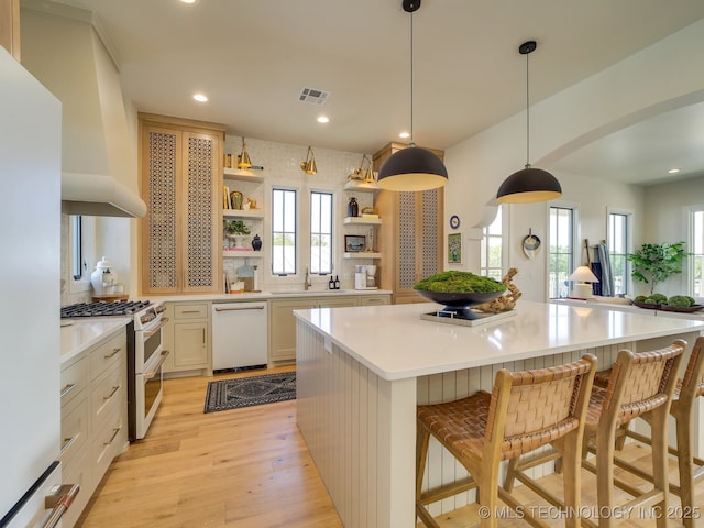 kitchen featuring a breakfast bar, tasteful backsplash, white appliances, a healthy amount of sunlight, and a large island