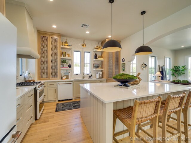 kitchen with white appliances, a center island, light countertops, light wood-type flooring, and open shelves