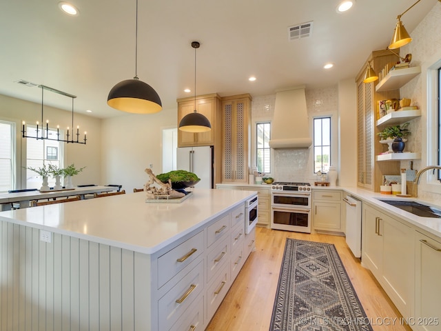 kitchen with premium range hood, white dishwasher, high quality fridge, white cabinets, and range with two ovens