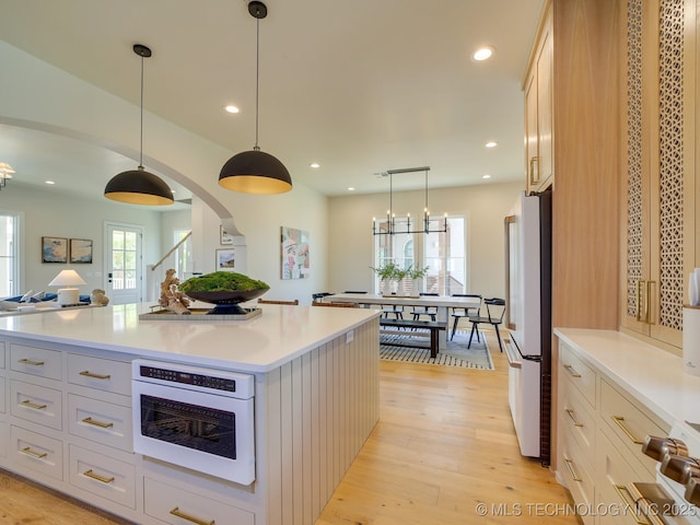 kitchen with decorative light fixtures, white cabinets, a center island, a healthy amount of sunlight, and white appliances