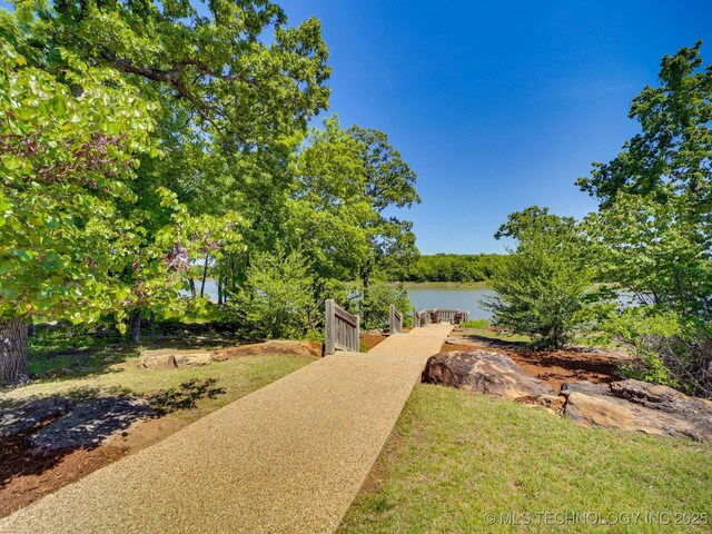 view of yard with a water view, driveway, and a boat dock