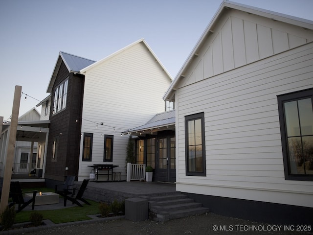 view of side of property featuring metal roof, a patio, an outdoor fire pit, and board and batten siding