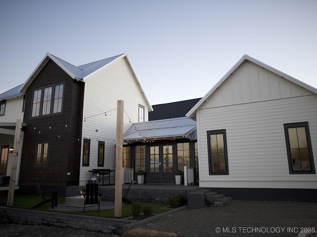 back of house featuring a patio, metal roof, board and batten siding, and french doors